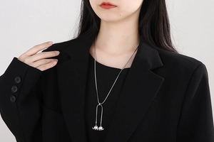 Detail of silver long snake chain necklace with twin elephant pendants on black suit