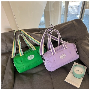 Macro detail of cylinder sports bags in green and purple colors on a grey sofa