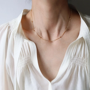 Close-up of gold snake chain necklace with small beads on a woman's neck