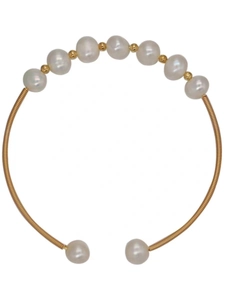 Detail of a handmade gold spiral bracelet featuring white pearls and ethnic retro style