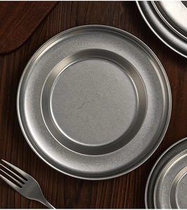 Flat lay of vintage stainless steel deep pasta plates on a rustic dark wooden table