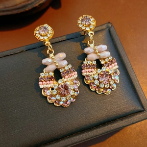 Detail view of vintage gold earrings with purple crystals and intricate beadwork