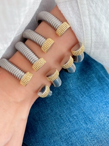 Detailed macro of stacked silver and gold spring spiral bangles with pavé textured ends