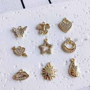 Nine gold plated DIY charms with rhinestones featuring heart, star and butterfly shapes