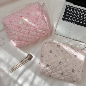 Detailed close-up of quilted floral and rabbit cosmetic bags on a laptop background