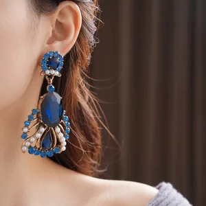 Vintage gold drop earrings featuring deep blue oval gemstone and pearls on model