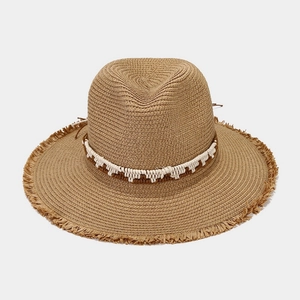 Detail of hand-woven straw hat featuring stylish frayed edges and a decorative ethnic band