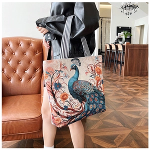 Detail of 3D peacock embroidery on canvas tote bag with striped shoulder strap