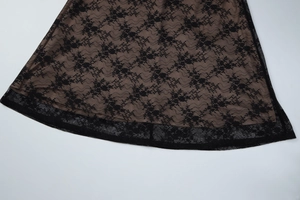 Detailed close-up of black floral lace fabric with nude lining on the dress hemline
