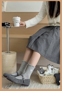 Detail of white knit crew socks featuring wavy cuffs and delicate bow embroidery
