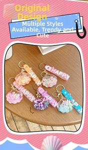 Detail of shell-shaped liquid glitter keychains with HAPPY strap in pastel colors