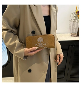 Close-up of brown suede skull wallet with sparkling rhinestones held by a model