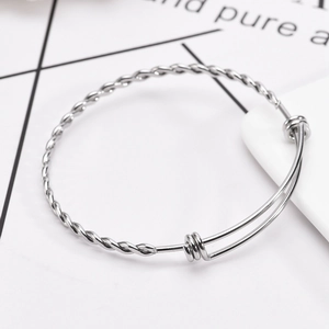 Polished silver stainless steel adjustable twisted rope bangle bracelet on white background