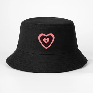 Dettaglio del ricamo a cuore multistrato su un cappello a secchiello in cotone nero