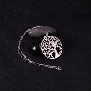 Detail view of silver tree of life pendant with owl on dark stones and black background
