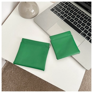 Detailed view of two bright green leather coin purses with metal snap closure on a desk