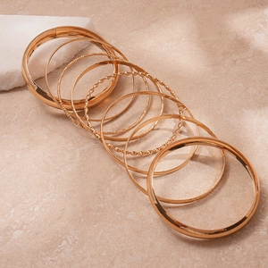 Detailed close-up of 8-piece gold geometric bracelets with varied textures and finishes