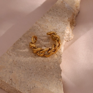 Close-up of golden Cuban chain ring on stone with soft pink silk background