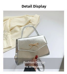Détail du sac bandoulière argenté brillant avec nœud doré et rabat style enveloppe