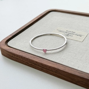 Detail of S925 silver heart bracelet with pink gemstone and small pavé diamonds