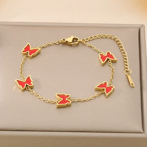 Detail of gold butterfly bracelet with red enamel charms and adjustable steel chain