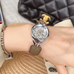 Close-up of a silver watch with a rotating diamond-encrusted petal dial and brown leather strap