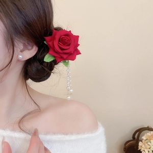 Close-up of red rose hair clip with long pearl tassel pendant on an elegant hairstyle