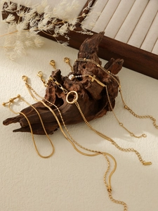 Detail of layered 18k gold plated titanium steel bracelets with gold beads on wood display
