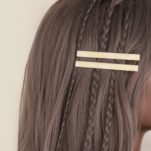 Elegant pair of cream yellow acetate hair clips styled on braided brunette hair
