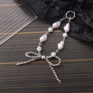 Detail of baroque pearl keychain with silver metal beads and sparkling glitter ball charm