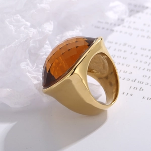 Close-up of golden stainless steel ring with a large faceted amber crystal stone