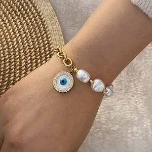 Detail of gold chain bracelet with pearl and crystal-encrusted evil eye charm