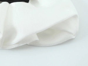Close-up of white satin patchwork top featuring elegant ruched texture and silky finish