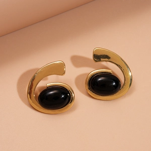 Détail de boucles d'oreilles spirales dorées vintage avec pierres en résine noire ovales