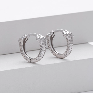 Macro shot of silver leopard head hoop earrings featuring detailed texture on white stands