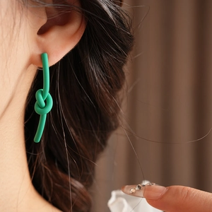 Close-up of a model wearing a matte green knotted earring with elegant minimalist design