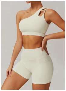 Detail view of off-white one-shoulder sports bra and high-waist shorts with side pocket
