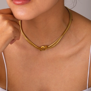 Detail view of a double-layered gold snake bone chain necklace with a stylish knot design