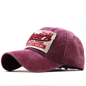 Dettaglio macro del cappellino da baseball bordeaux lavato con patch ricamata retrò