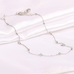 Detail of stainless steel O-chain necklace with polished beads on white silk fabric