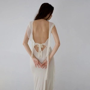 Detail view of the elegant backless white maxi dress with delicate ruffle and bow tie design