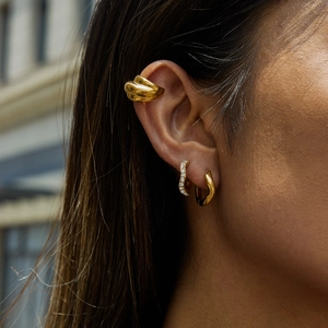 Close-up of model wearing 18K gold stainless steel ear cuffs and huggie hoop earrings