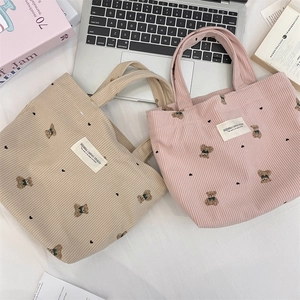 Detail of corduroy texture and bear embroidery on beige and pink mini handbags