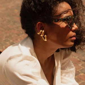 Élégantes boucles d'oreilles créoles dorées en C portées par un mannequin à l'extérieur