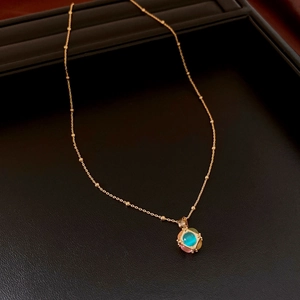 Close-up of 18K gold plated necklace with colorful opal square pendant on black texture