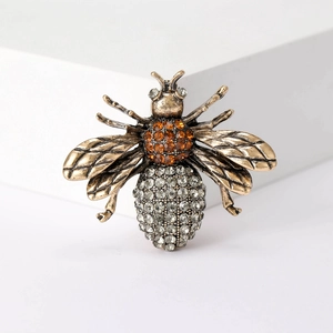 Macro shot of vintage bee brooch with orange and silver rhinestones on gold metal