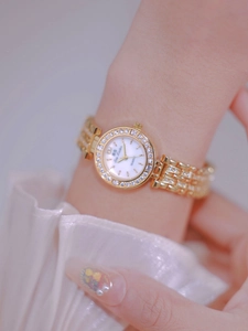 Close-up of a gold quartz watch with a diamond-studded bezel worn on a wrist