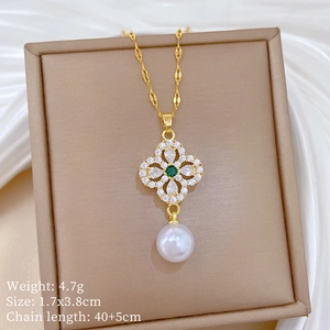 Detail of clover pendant with green gemstone, white diamonds and pearl on silk