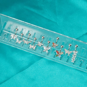 Selection of butterfly belly rings with zircons on elegant green silk background