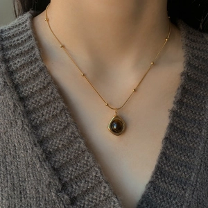Retro stainless steel necklace with round tiger eye stone pendant on a gold beaded chain